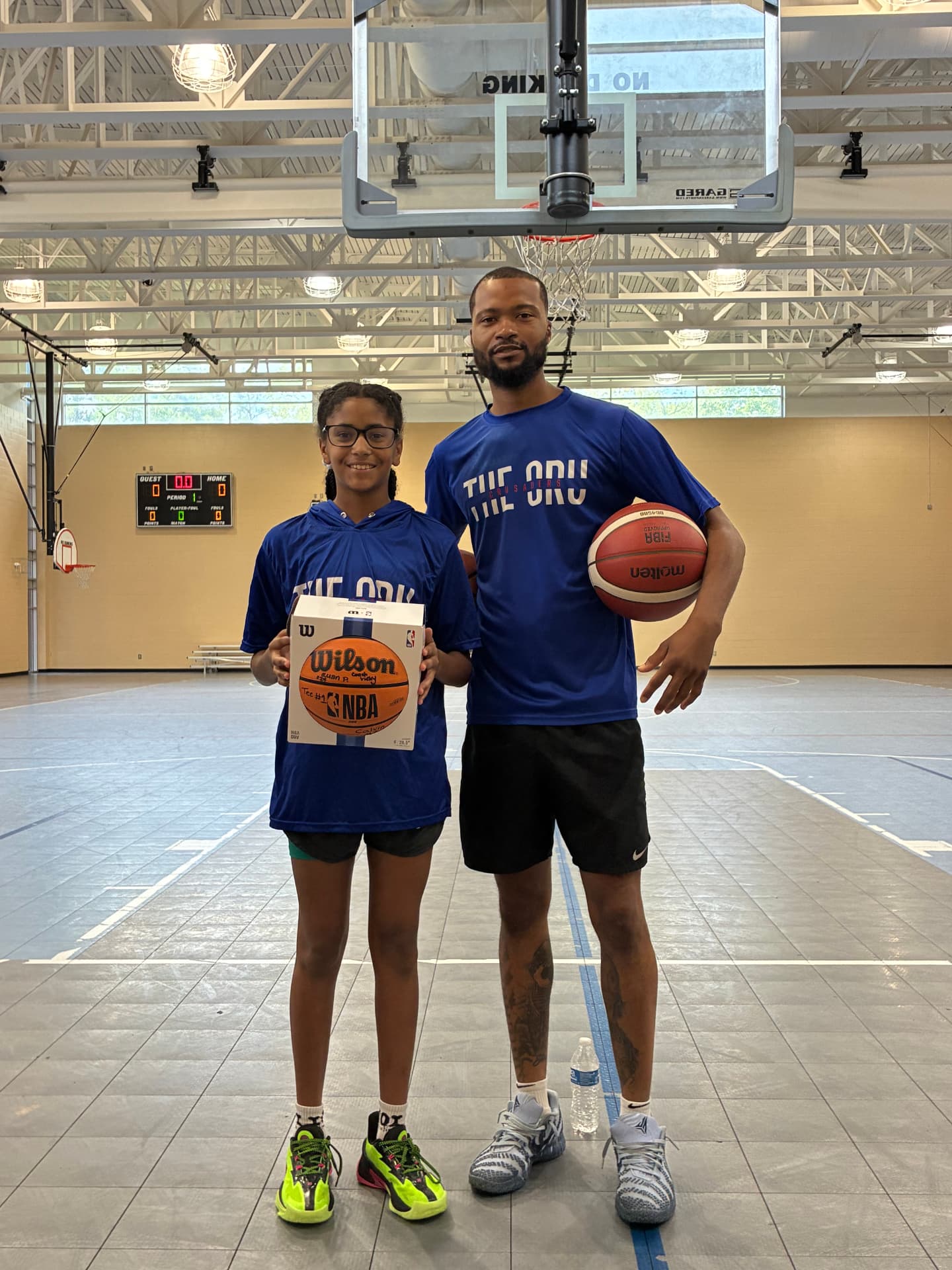 A mini camp participant receiving a basketball award from a coach